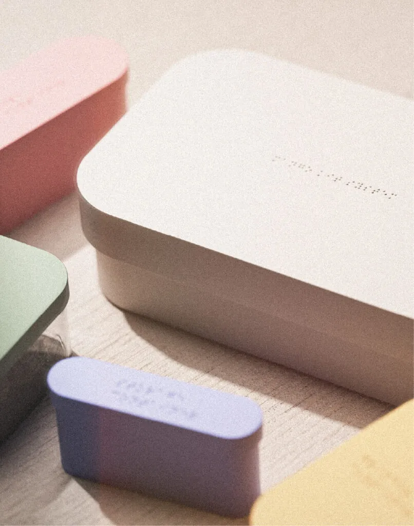 Pastel-colored boxes on a wooden surface in soft lighting, hinting at a cozy ambiance. Mango storage system by All Design Lab.