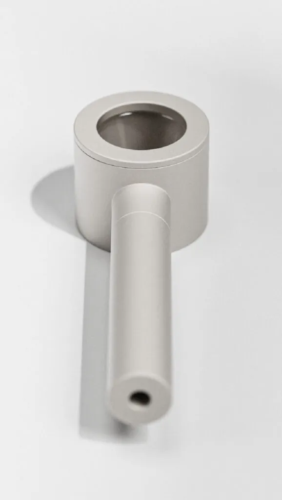 Minimalist metal pipe with a cylindrical mouthpiece on a white background. Mango Storage System by All Design Lab.