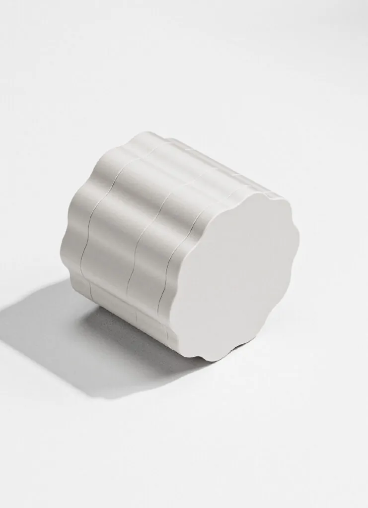 A sculpted, matte-finished metal grinder on a white surface with a soft shadow. Mango Storage System by All Design Lab.