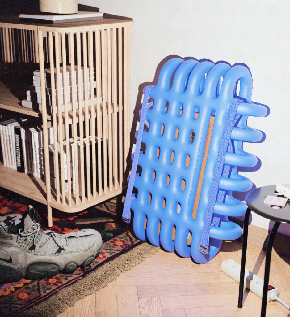 Blue foam cage like object on wooden floor and next to wall. Mega Mesh Backpack by All Design Lab.