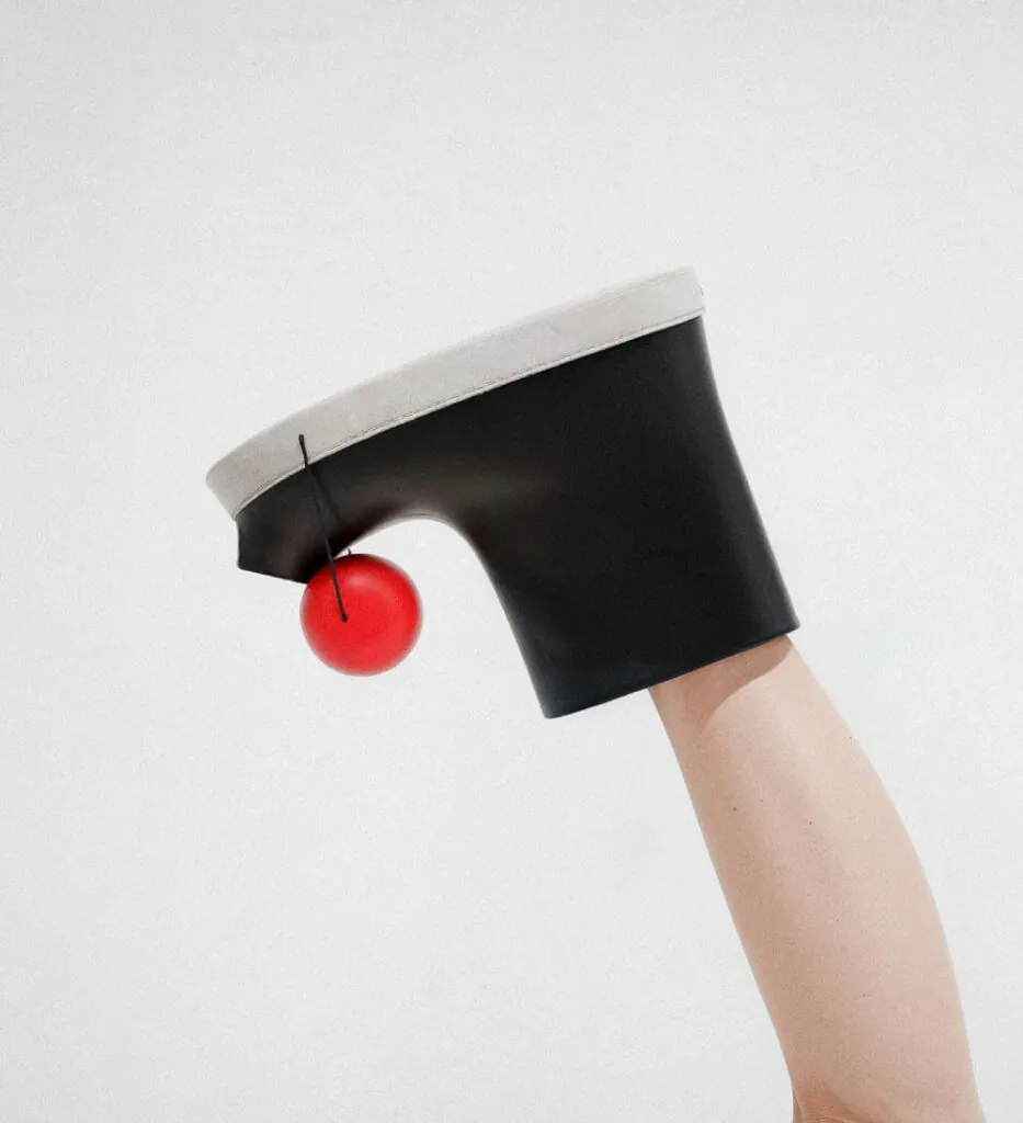 Leg, black boots, red ball, white background. Pom footwear by All Design Lab.