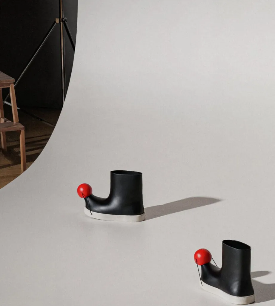 Red ball on black boots in studio background. Pom footwear by All Design Lab.