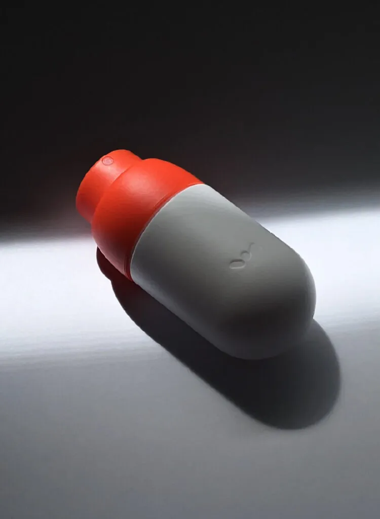 An orange and white spray bottle on a white floor with a ray of sunlight. NOK Pop refillable spray bottle by All Design Lab.