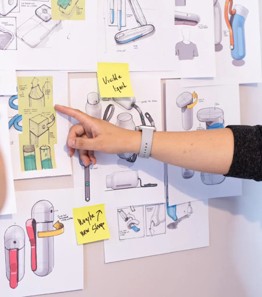 A hand pointing to sketches on a wall. NOK Pop refillable spray bottle by All Design Lab.