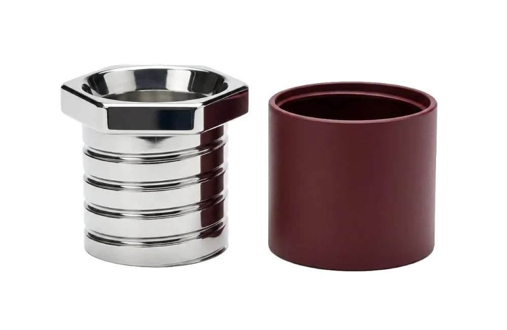 Exploded view of Esagono espresso cup showing mirror-polished stainless steel inner cup with threaded exterior separated from burgundy powder-coated aluminum sleeve