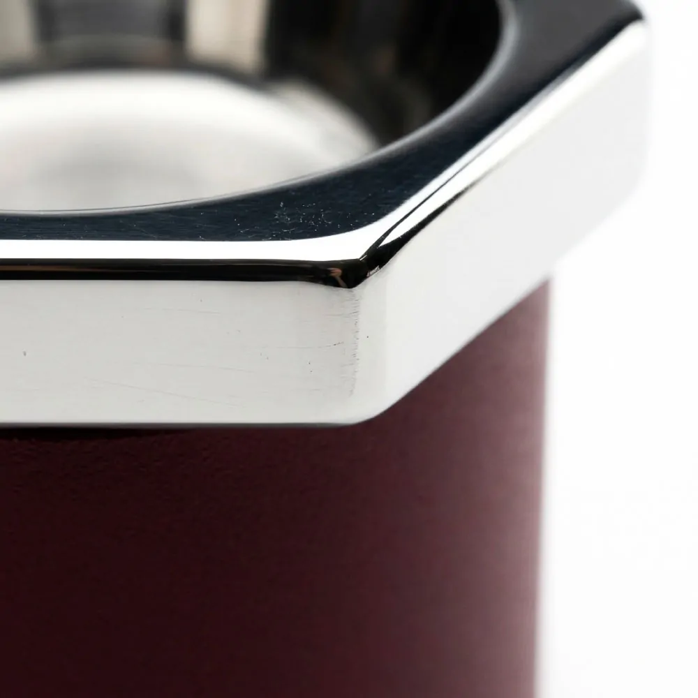 Close-up detail of Esagono espresso cup mirror-polished stainless steel hexagonal collar transitioning to burgundy matte aluminum body, chamfered rim edge detail